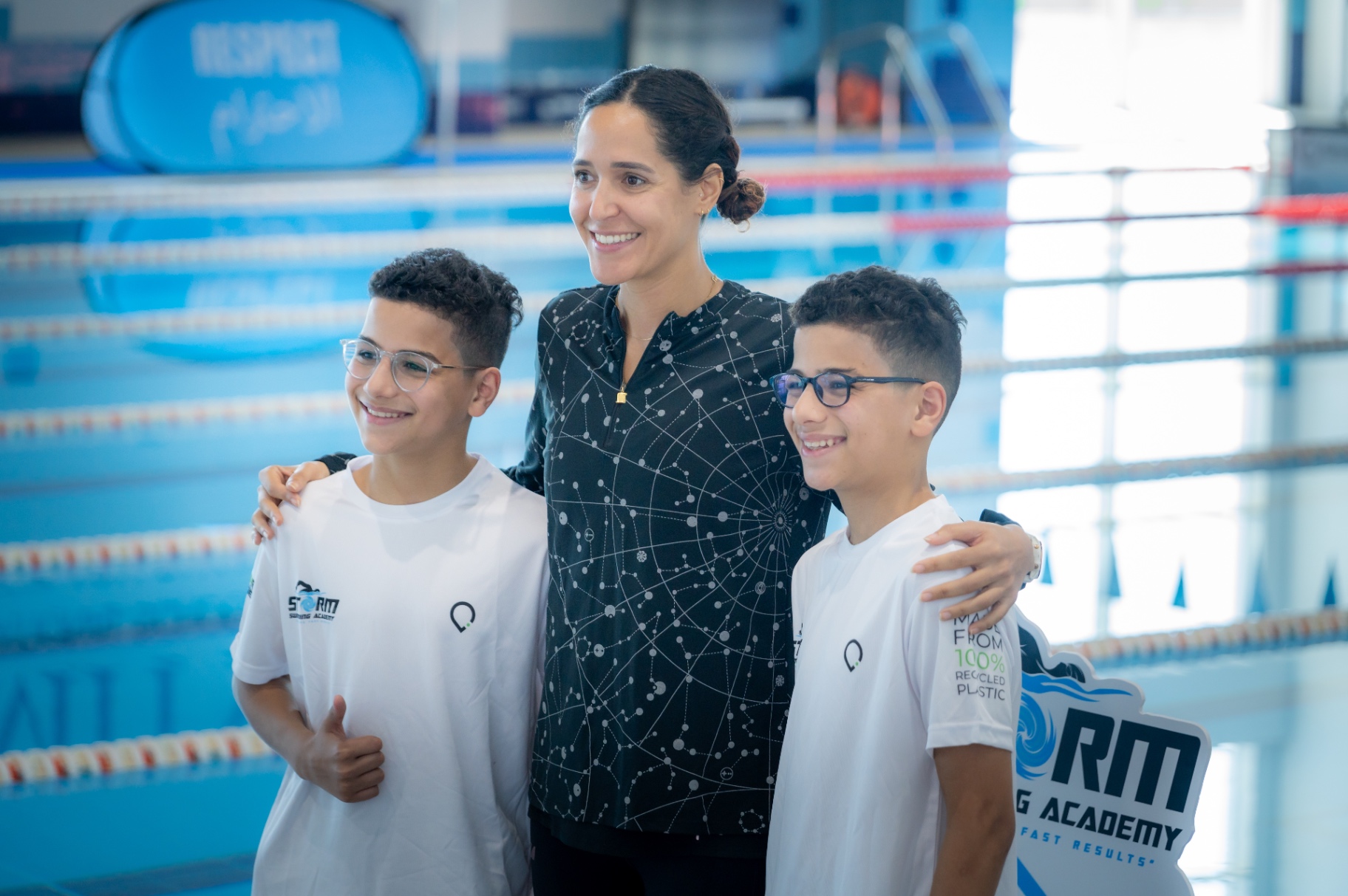 Dr Sarra Lajnef-Taylor smiling with young Storm Swimming Academy athletes