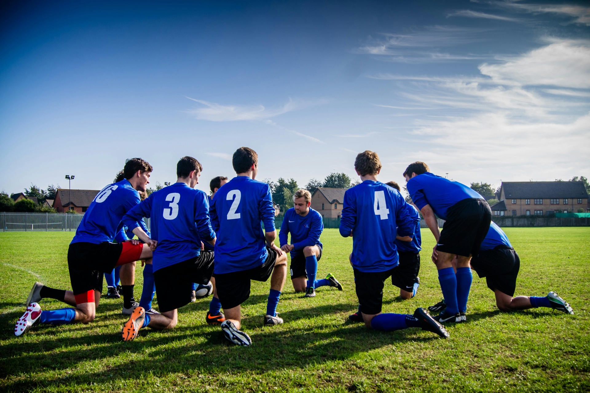 Football team huddle during training on a grass pitch